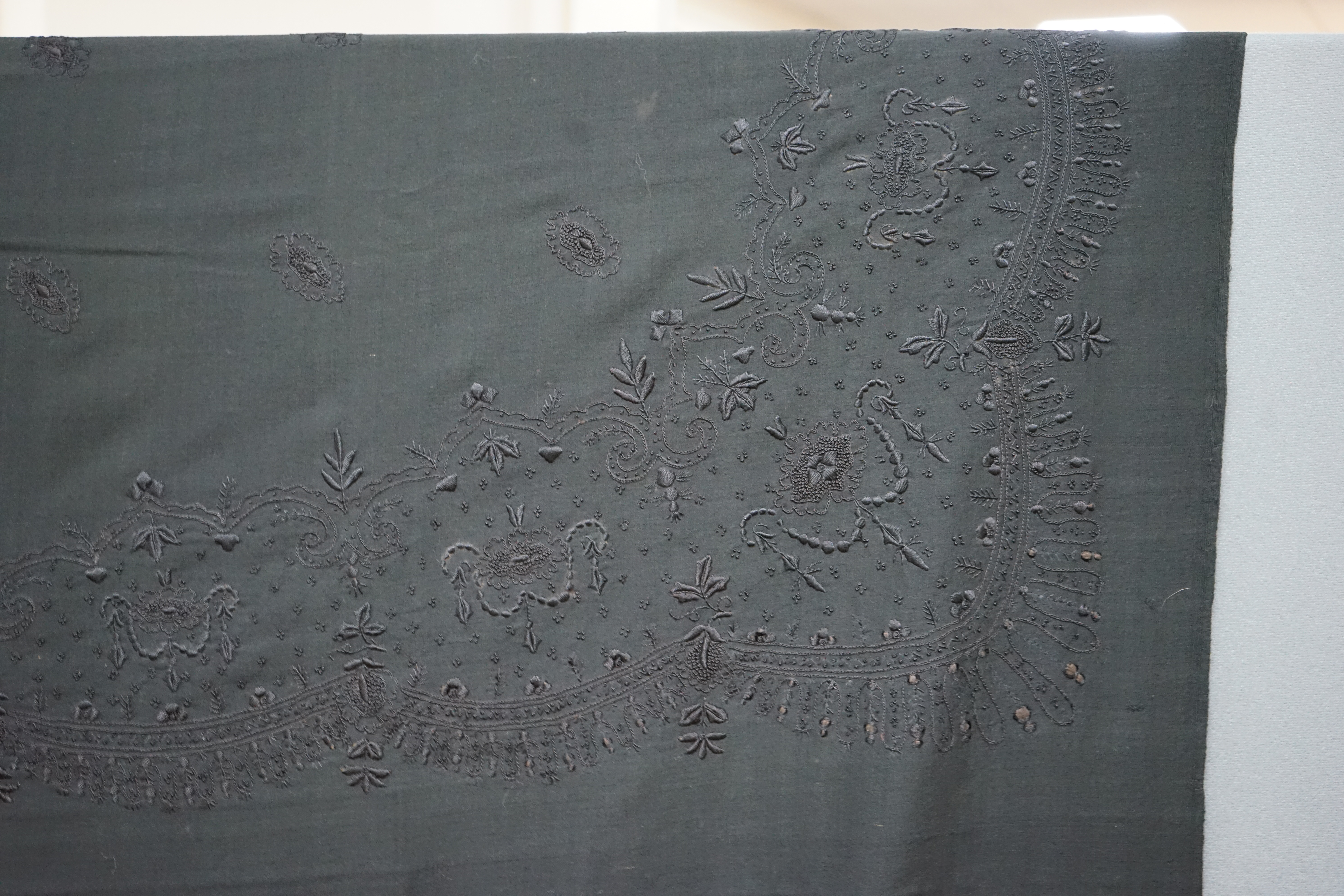 A fine example of a 19th century Paisley shawl and a simple black embroidered wool mourning shawl, the Paisley shawl has a central cream cartouche and a large teardrop design, amongst many decorative woven shapes, all in